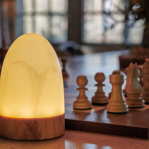 tafellamp met houten voet naast een schaakbord