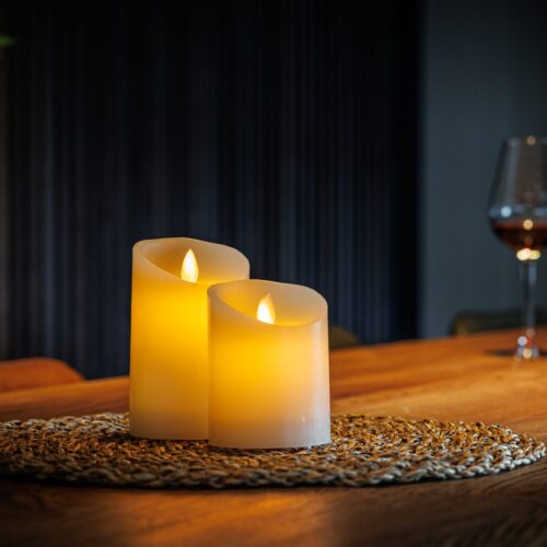Twee oplaadbare kaarsen van Dorsetto op een placemat op tafel met op de achtergrond een fles en een glas wijn
